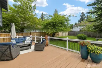 Fully fenced backyard ready for every activity: All-weather deck, level lawn and garden space, shed, playset to stay, and concrete flat top with basketball hoop!