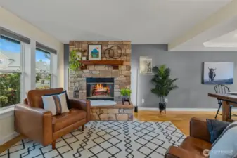 Front facing living room with tinted windows for privacy and energy efficiency, wood burning firelpace, open to dining room with continuous flow/access into kitchen.