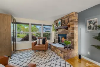 Front facing living room with tinted windows for privacy and energy efficiency, wood burning firelpace, open to dining room with continuous flow/access into kitchen.