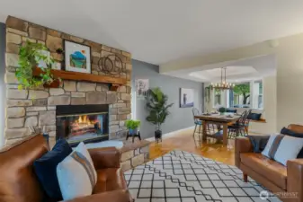 Front facing living room with tinted windows for privacy and energy efficiency, wood burning firelpace, open to dining room with continuous flow/access into kitchen.