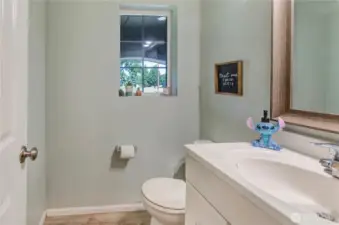 Charming and light-filled half bath with a modern vanity, natural light, and playful personality—perfect for guests!