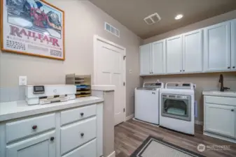 Multi-functional laundry room with extra storage, work space and a sink.