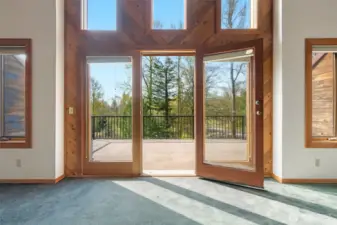 French doors lead to a peaceful treetop deck, filling the room with light and possibility. Swap the carpet for new flooring and this space transforms—simple update, big impact.