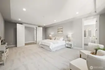 French doors open into the primary suite that boasts a coffered ceiling, capacious feel, deck access, and its own private ensuite.