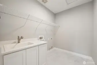 Dedicated laundry space, complete with a utility sink, cabinets, and dryer hook-up with both gas and electric.