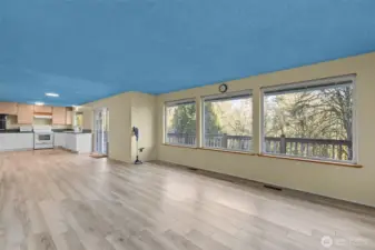 Living room, kitchen, and dining area featuring large picture windows and a sliding glass door to the deck.