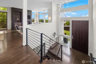 Entry featuring 13' ceilings, solid oak flooring, tig-welded custom steel railings