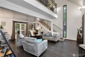 The living room view from the hallway shows the stairs up to loft area and Bonus area currently being used as the primary bedroom.