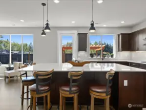 The focal point of the space is the massive entertainment-style island, adorned with luxurious quartz countertops and offering ample bar seating, creating a central hub for both cooking and socializing.