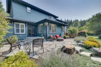 Elegant French doors open onto a stunning stone patio, creating a seamless transition between indoor and outdoor living.  This outdoor retreat extends the home’s living space while enhancing its sophisticated yet inviting ambiance.