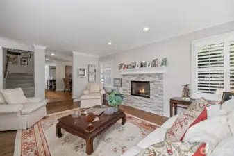 From this perspective, the sunken living room opens gracefully toward the kitchen and dining areas, showcasing the home’s open-concept layout. The hardwood floors flow seamlessly throughout, while large windows fill the space with natural light, highlighting the elegant finishes and inviting ambiance. This view emphasizes the perfect balance between intimate living spaces and social, entertaining areas, making it ideal for family gatherings or hosting guests.
