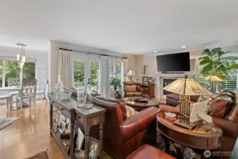 The elegant family room serves as the heart of the home, where comfort meets sophistication. Gleaming hardwood floors and a striking fireplace create a warm and inviting atmosphere, perfect for both quiet evenings and lively gatherings. The open-concept design flows seamlessly into the gourmet kitchen, allowing effortless connection between cooking, dining, and relaxing. Large windows frame serene views of the property, filling the space with natural light and enhancing its welcoming ambiance.  Elegant French doors open gracefully to reveal lush acreage beyond, creating a seamless connection between indoor and outdoor living. Sunlight pours through the glass panes, illuminating the interior while offering sweeping views of verdant landscaping and mature trees. This inviting transition enhances the home’s sense of openness and tranquility, making every step toward the outdoors feel like a private escape.