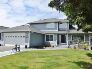 Front of the home w/ Covered Front Deck.  Concrete Patio and Walkway leading to the Front Deck/Door.