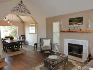 Living Room w/ vinyl plank flooring, propane fireplace insert, and leading into the Dining Room.