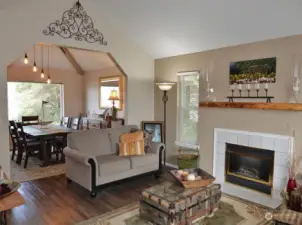 Living Room w/ vinyl plank flooring, propane fireplace insert, and leading into the Dining Room.