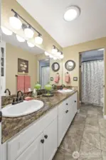 The guest bath includes a pocket door to the primary bedroom and enjoys double sinks.