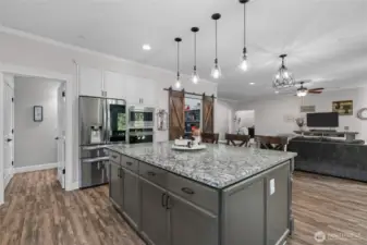 Chef's kitchen with large center island, stainless appliances and granite countertops.