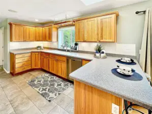 Beautiful kitchen with loads of hickory cabinets, solid surface counters, eating space with skylight above and breathtaking view of the rear yard from the kitchen window.