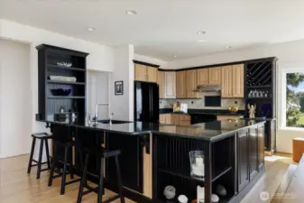 Cook's Kitchen in the Open Floor Plan with Hickory cabinets & flooring, Quart countertops & Tile surround, Black appliances, and eating area.