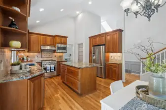 Here's the Gourmet Kitchen with cherry cabinets, slab granite, stainless appliances, tiled backsplash and an island with seating.
