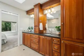 This is the remodeled primary bath with cherry cabinets, with storage cabinet on the granite countertops and linen storage to the right.