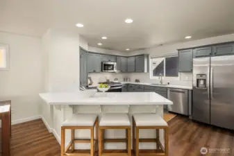 Open concept kitchen includes spacious bar seating with room for four oversized stools.