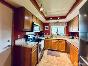 Kitchen with stainless steel appliances, amply cupboards and granite countertops, LVP flooring, with updated lighting, access to garage that is sheetrocked