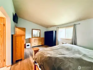 Primary suite view from the entryway, vaulted ceiling, LVP, spacious layout, dual closets and 3/4 bathroom ensuite with make up counter