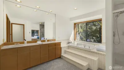 The spacious primary bathroom en suite offers a luxurious tub with views to the PNW beauty just outside, walk-in shower and double sink vanity.