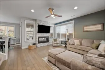 Light and welcoming great room with ceiling fan, gas fireplace and views to the backyard