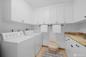 Dedicated laundry room with abundant cabinetry, counter space, and utility sink for added convenience and storage.