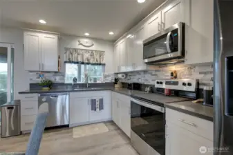 Slab countertops and gorgeous custom tile backsplash make for a kitchen that is pleasing to the eye.