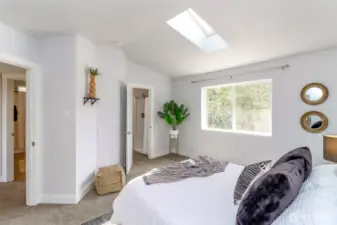 This view of the primary suite highlights the large window that frames the tranquil backyard and the serene protected green space beyond.