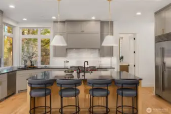 Bright and open chefs kitchen with commercial grade Wolf/Subzero appliance package, Large island with prep sink, and custom built cabinet details with matching flush commercial grade hood cover