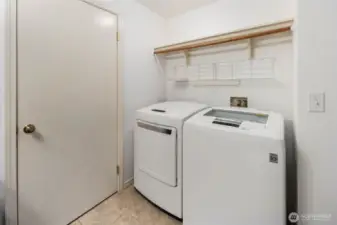 Main level laundry room within the 1/2 bathroom. Wood + wire shelving above washer and dryer.