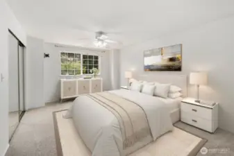 Virtually staged primary bedroom view from the door. Dual closets with mirrored doors on the left wall and one window facing the front of the home.