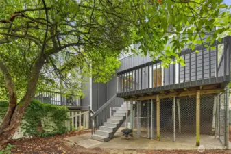 View of the back deck, stairs, and gated under-deck storage.