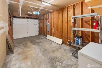 1-car attached garage with deep freezer and wall shelves.