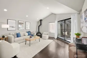 The living area features vaulted ceilings, a cozy gas-fireplace, rich espresso hardwood floors and a deck with a peek view of the Sound.