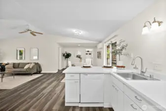 L shaped kitchen layout with refreshed white cabinets and countertops. Dishwasher located to the left of sink.