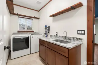 Large utility room with built in sink/cabinets with granite countertop.