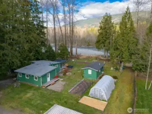 Stunning aerial view of Nooksack Riverfront property featuring private beach, outbuildings, greenhouse, and expansive usable grounds.