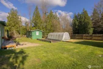 Two hoop-style greenhouses, raised garden beds, and detached outbuilding ideal for shop, studio, or flexible use.