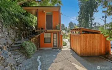 Street view of driveway entrance (north side) with parking for 2 cars tandem..  View of the Cottage (North) home and custom shed for the garbage/recycle/green bins.