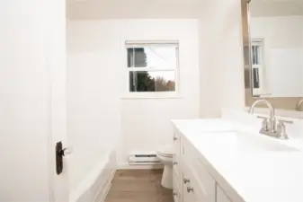 The bathroom is updated with an over-sized vanity with tons of storage, new fixtures, a new mirror, and all new flooring.