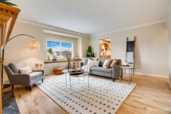 The living room fills with light through the bay window where a built-in shelf is ready for house plants.