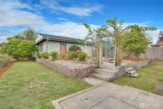 In the fenced yard, climbing roses, hydrangea, iris, and lilac surround the patio beside the 2-car garage and workshop.