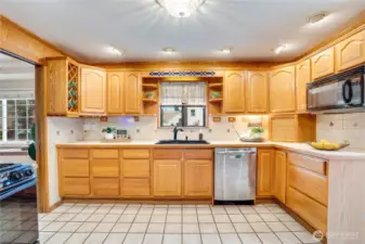 The eat-in kitchen features a tile floor and decorative tile backsplash along with a box window for sprouting seeds or keeping fresh kitchen herbs. Notice the wide array of cupboards and drawers.