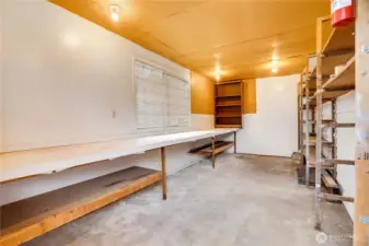 Take a door from the parking area into this workshop with an east window and a work table stretching the whole length of the room.