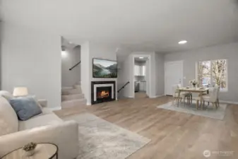 Main living area with new LVP flooring, light fixtures and wood trim. Virtually staged.